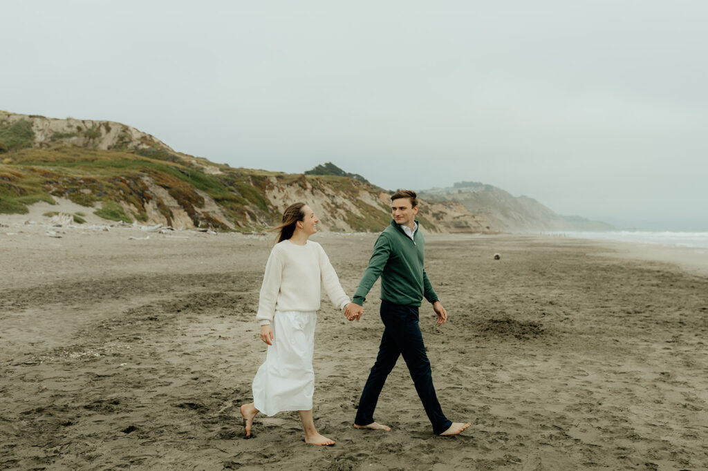 couple holding hands walking around the beach