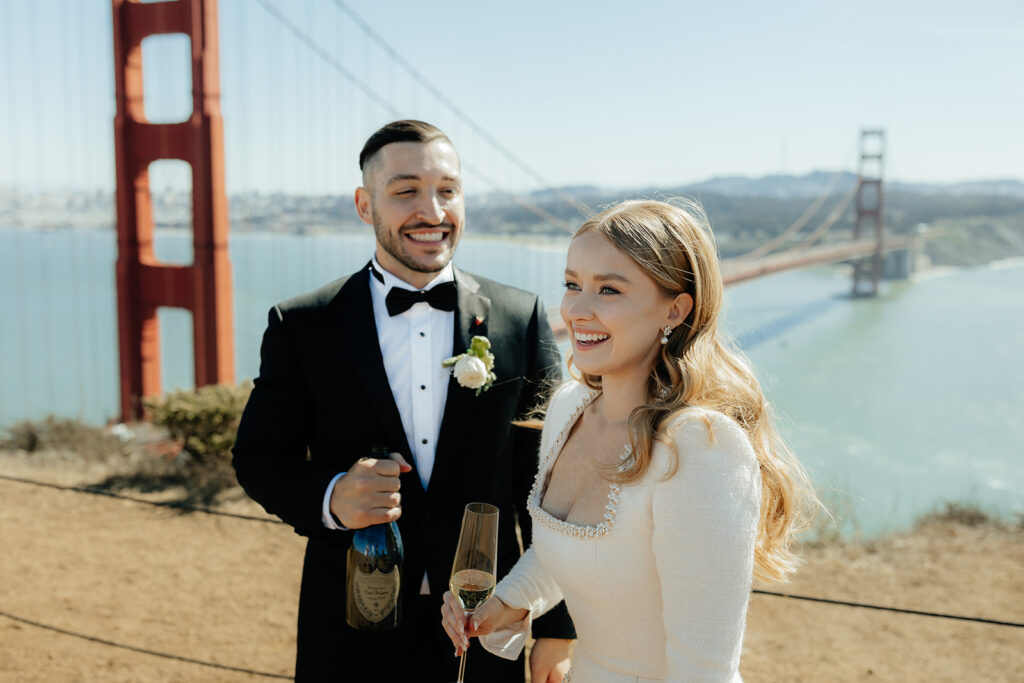 Elopement Couple at San Francisco Golden Gate bridge with champagne groom looking at bride sweetly