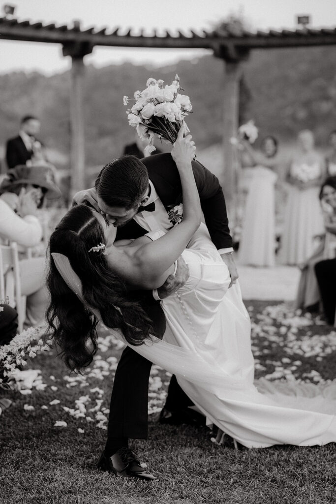 Clos LaChance Wedding ceremony bride and groom dip kiss black and white image