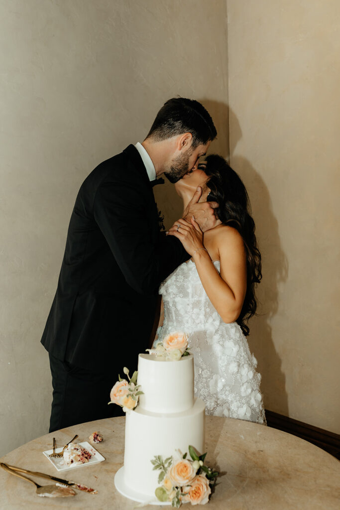 Clos LaChance Wedding bride and groom kissing in front of cake