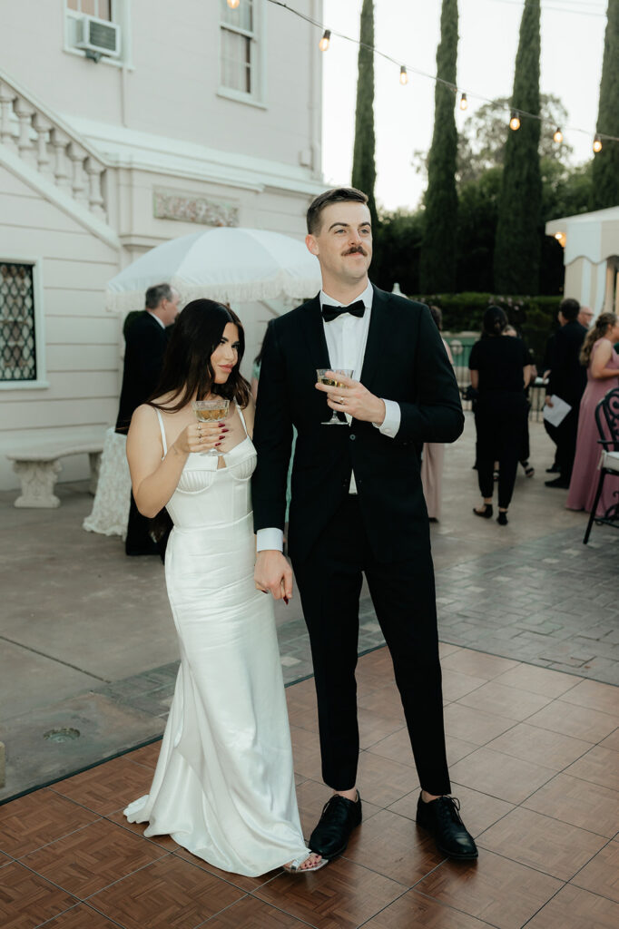 Grand island mansion wedding chic couple at cocktail hour holding drinks