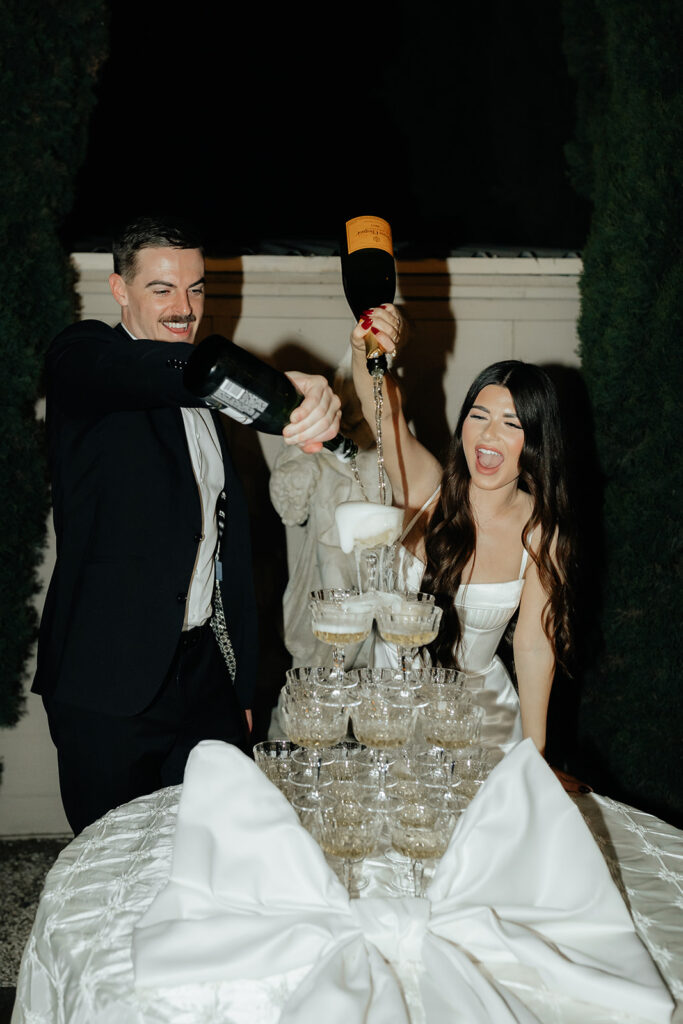 Grand island mansion wedding chic couple pouring champagne on tower of glasses