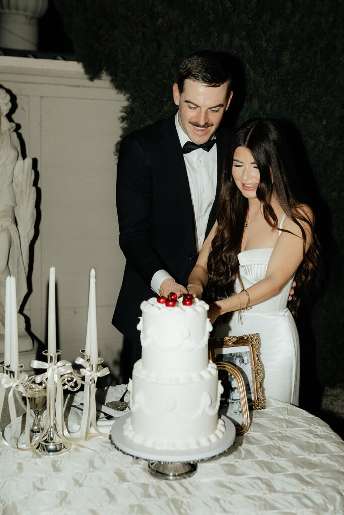 Grand island mansion wedding chic couple cutting vintage white cake with cherries on top